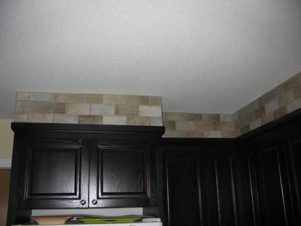 Tile installed above cabinets ,to complete the stone kitchen appeal - Nice Touch !